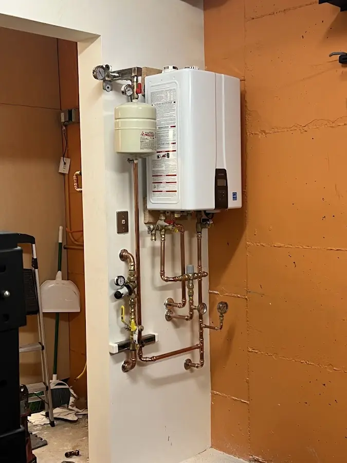 Plumbing technician inspecting water heater connections in Dannemora
